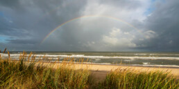 Zicht vanaf duinen op regenboog boven zee op het strand bij Egmond-Binnen | © Ronald van Wijk Fotografie