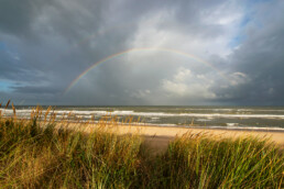 Zicht vanaf duinen op regenboog boven zee op het strand bij Egmond-Binnen | © Ronald van Wijk Fotografie