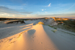 Ochtendlicht schijnt over slingerend zand aan de voet van een groot stuifduin in de Meeuwenlekken bij Bergen aan Zee | © Ronald van Wijk Fotografie